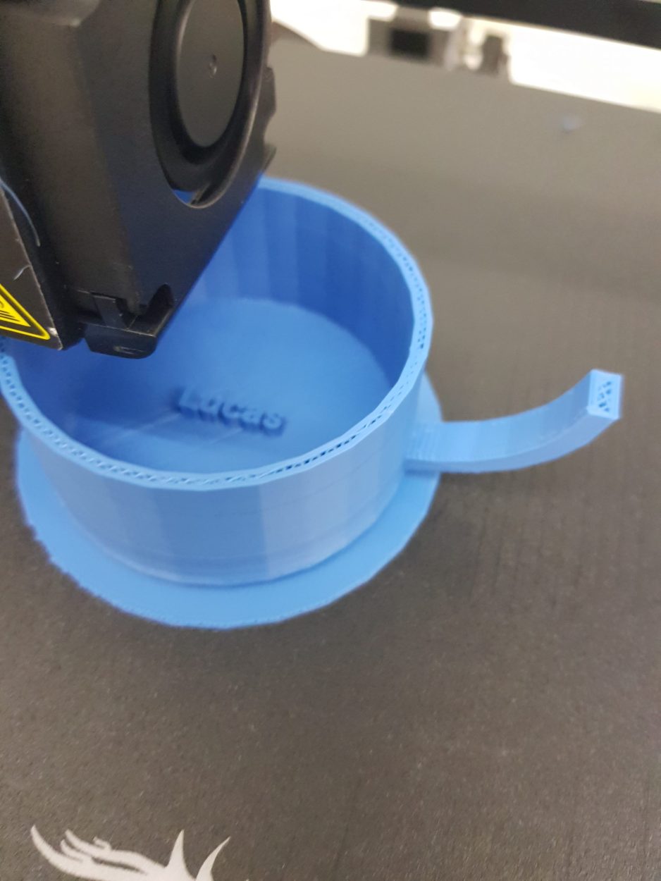 Das Bild zeigt wie ein 3D Drucker eine Tasse mit einem Namen druckt