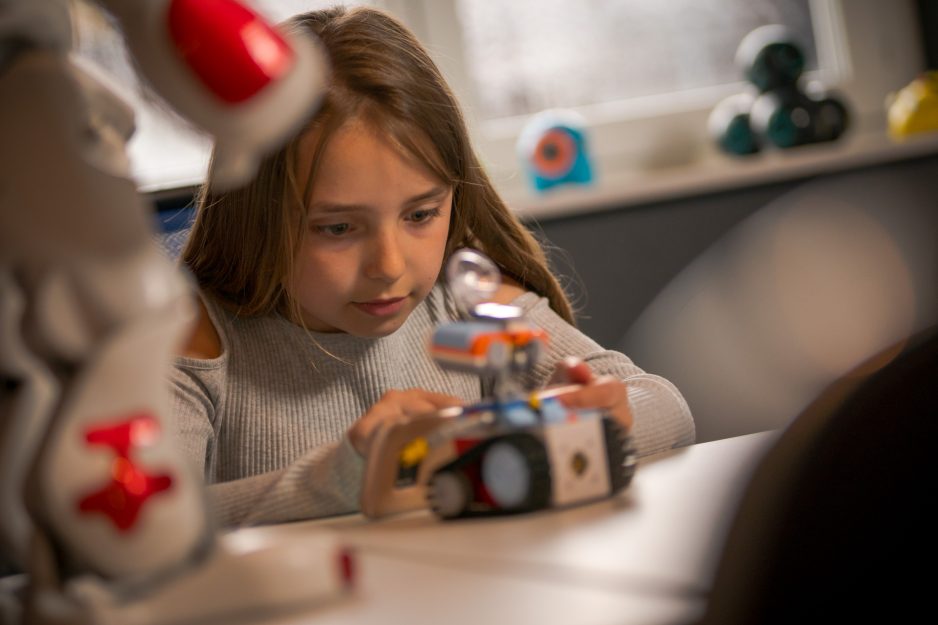 Ein Mädchen programmiert einen kleinen Kinderroboter